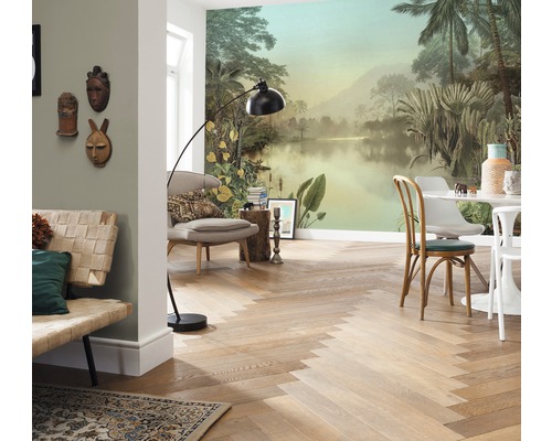 Vardagsrum med tropisk fototapet, trägolv i fiskbensmönster, sittmöbler och golvlampa.