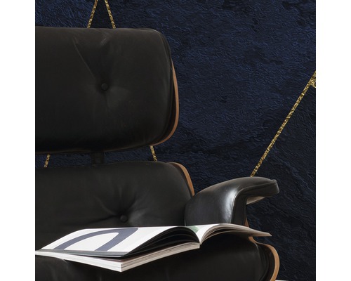 Detaljvy av en fåtölj med tidning framför en vägg med geometriskt mönster