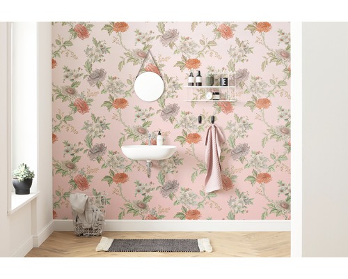 Badrum med blommig tapet, spegel, handfat och handdukshållare.