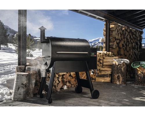 Traeger grill med vedstapel i bakgrunden