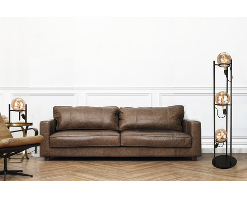 Vardagsrum med brun lädersoffa och golvlampa med flera glödlampor