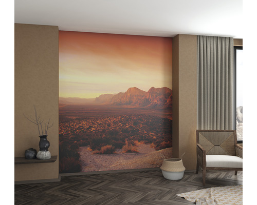 Vardagsrum med fototapet som visar ett bergslandskap i solnedgången.