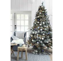 Dekorerad julgran med ljus, julgranskulor och rustika dekorationer i ett vardagsrum.