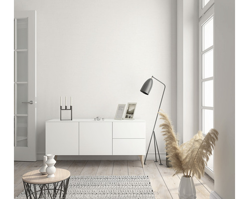 Ljust vardagsrum med byrå, golvlampa och dekorationsartiklar