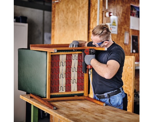 Man fäster tyg med häftpistol på stol