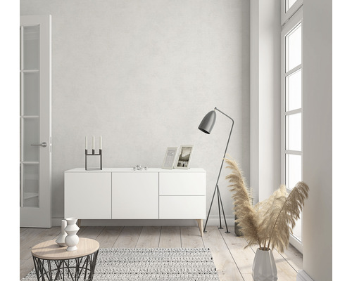 Ljust vardagsrum med vit skänk, golvlampa och dekorationer.