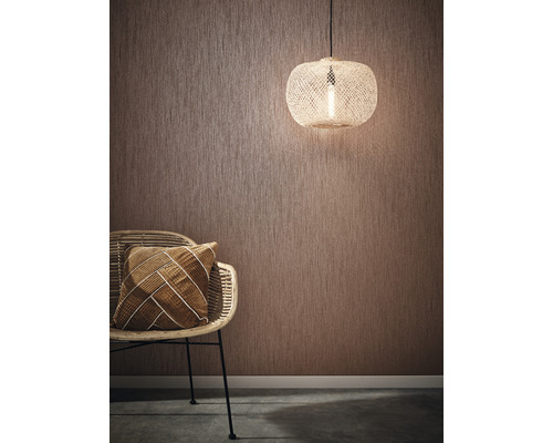 Rumsscen med strukturtapet, rottingfåtölj, kudde och taklampa