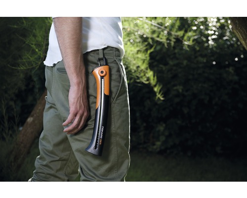 Man med Fiskars handsåg i byxfäste i trädgården