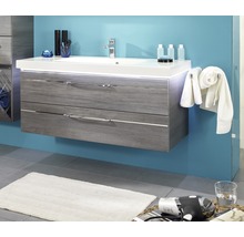 Tvättställ med två lådor, armatur och handdukar framför en färgad vägg