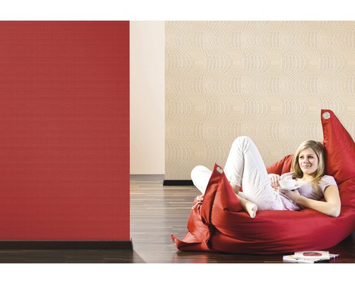 Kvinna kopplar av på sittsäck framför röda och beige mönstrade tapeter