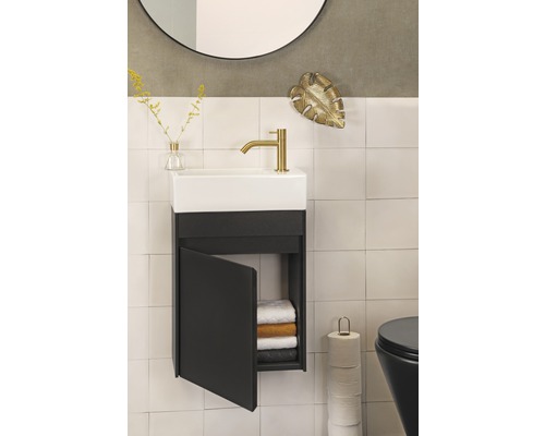 Badrum med handfat, underskåp med öppen dörr, handdukar, toalett, spegel och dekoration