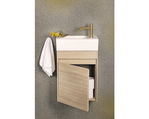 Hängande tvättställ med öppen dörr, handduk och gyllene armatur