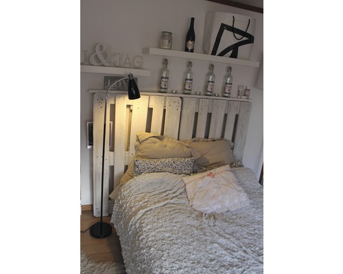 Sovrum med säng, sänglampa och hyllor