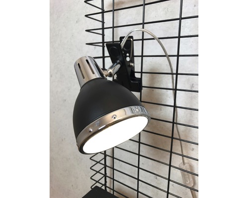 Svart klämspotlight fäst på ett galler