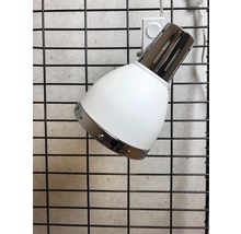 Vit spotlight med metallelement på en gallervägg