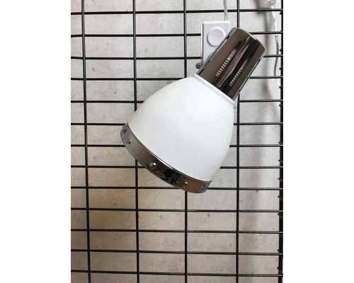 Vit spotlight med metallelement på en gallervägg