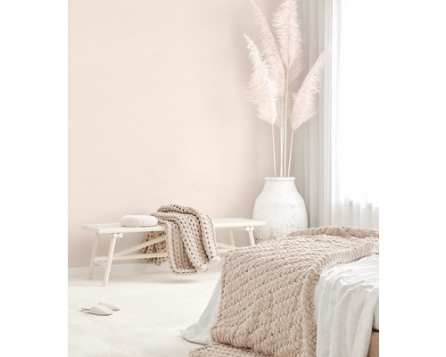 Ljust sovrum med säng, bänk, filtar, kuddar och pampasgräs i en vas