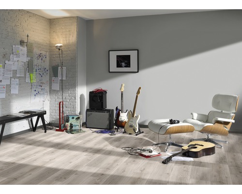 Ljust rum med gitarrer, förstärkare, fåtölj och laminatgolv