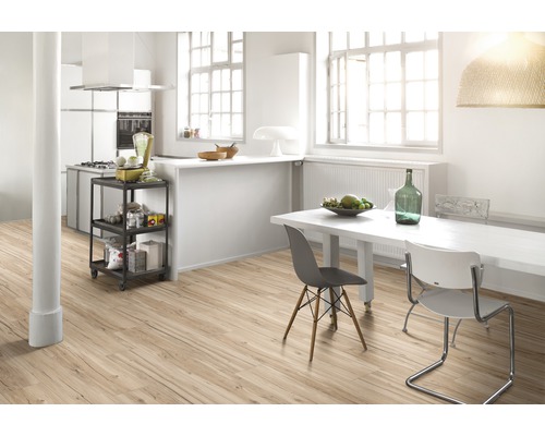 Ljust kök med trägolv, matbord och köksvagn.