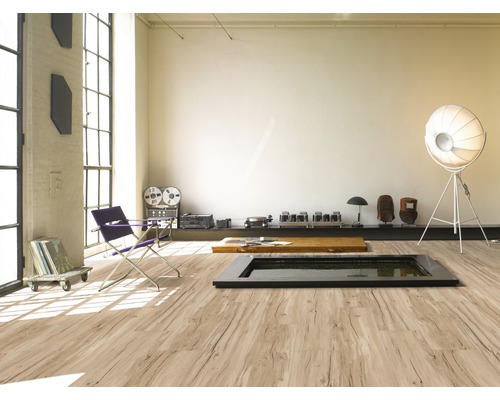 Ljust rum med stort fönster, laminatgolv i träutseende, sittmöbler och dekorationer.