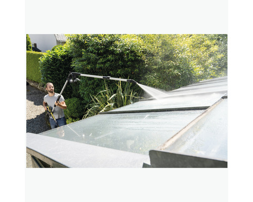 Man rengör växthustak med högtryckstvätt och lans