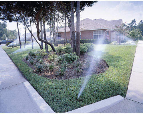 Bevattningssystem för en gräsmatta och en trädgårdsyta framför ett bostadshus.