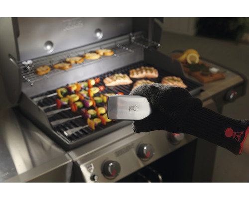 Öppen grill med grillad mat som kött och grönsaker, grillhandske håller temperatursensor