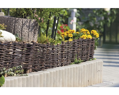 Dekorativ rabattkant av vide och betongstenar i trädgården.