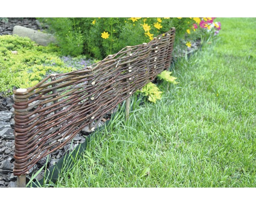 Trädgårdsscen med ett lågt staket av flätade grenar