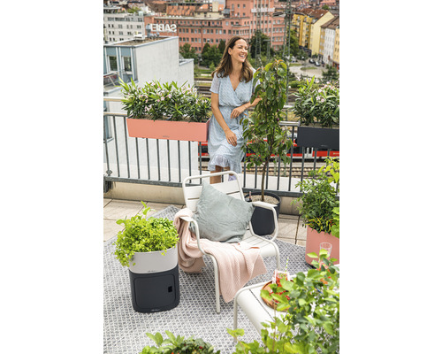 Balkongscen med kvinna, stol, planteringar och utsikt över staden