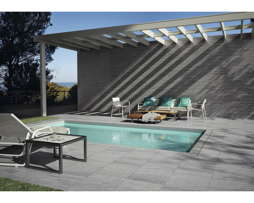 Uteplats med pool, kakelgolv, kakelvägg, pergola och trädgårdsmöbler.