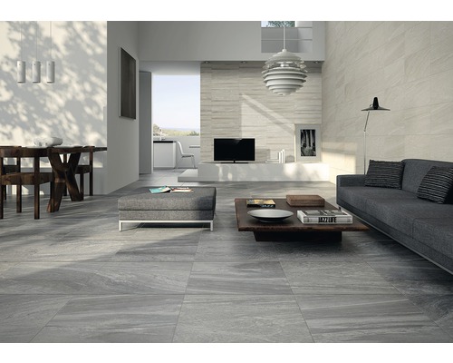 Modernt vardagsrum med grå golvplattor, soffa och matbord