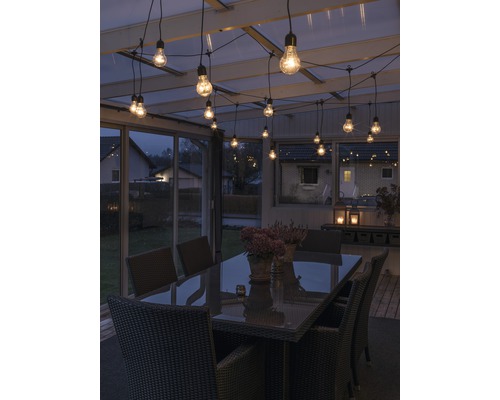 Terrass med bord, stolar och ljusslinga för en stämningsfull atmosfär.