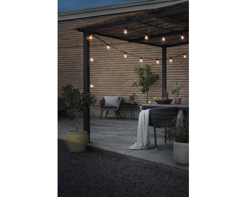 Uteplats med pergola, ljusslinga och trädgårdsmöbler på en träterrass