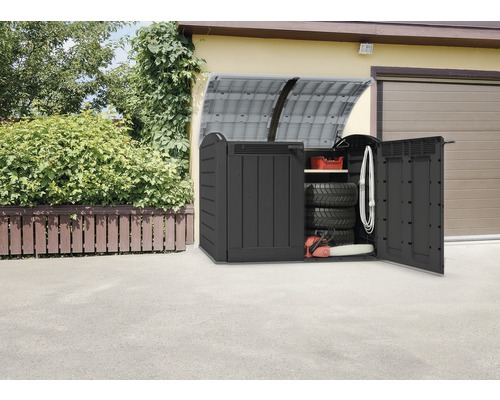 Öppen förvaringslåda i plast för verktyg med tillbehör framför ett garage