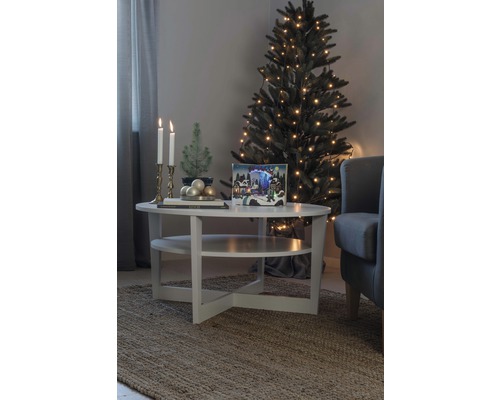 Julrumsscen med julgran, ljus och dekorationer på ett bord
