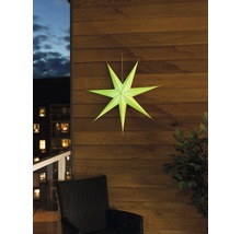 Dekorativ pappersstjärna på en trävägg, med en stol och en växt i bilden.