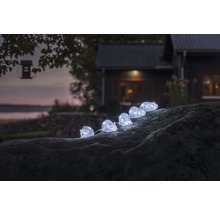Dekorativ ljusslinga med igelkottsmotiv på en sten i trädgården.