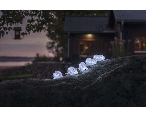 Dekorativ ljusslinga med igelkottsmotiv på en sten i trädgården.
