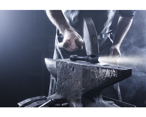 En Varta ficklampa på ett städ, med en hammare ovanför