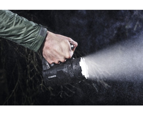 En person håller en Varta handlampa i regnet.