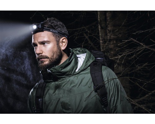 Man med Varta pannlampa och ryggsäck utomhus