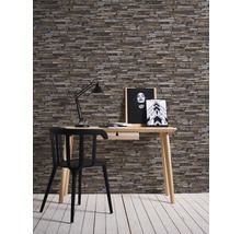 Inredning med skrivbord, stol, lampa och vägg i stenlook för arbetsrum eller kontor.
