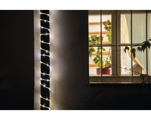 Utomhusvy av ett hus med en ljusslinga lindad runt en pelare och ett fönster med växter.