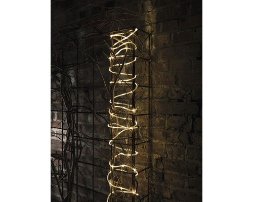 Dekorativ ljusslinga på ett metallgaller mot en tegelvägg