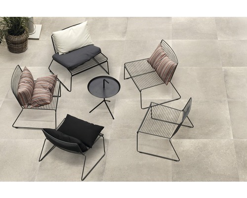 En loungehörna med fyra metallstolar och ett litet bord på uteplatsplattor