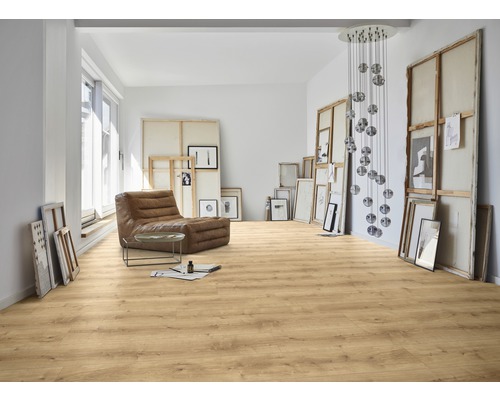 Ljust rum med laminatgolv, fåtölj och konstverk.