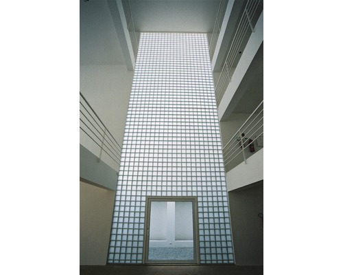 Interiörbild av en byggnad med en vägg av glasbetong och en dörr