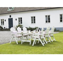 Vit trädgårdsgrupp med bord, stolar och dynor på en gräsmatta framför ett hus