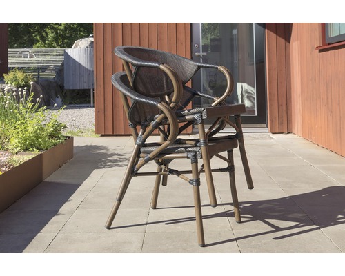 Två trädgårdsstolar i rotting staplade framför en byggnad.